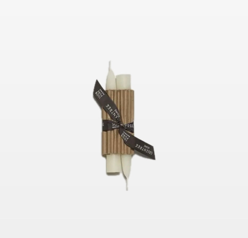 A pair of white candle tapers tied together with a black ribbon, against a white background.