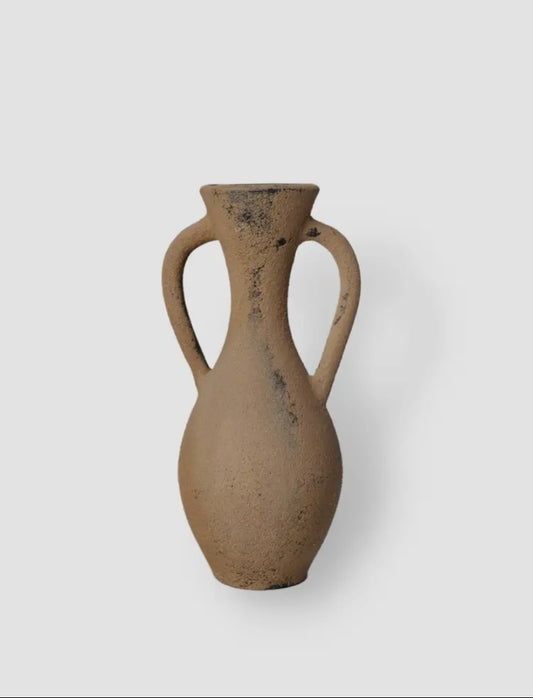 The handmade Amil ceramic vase features a rustic umber tone and textured design, with two handles and a narrow neck.