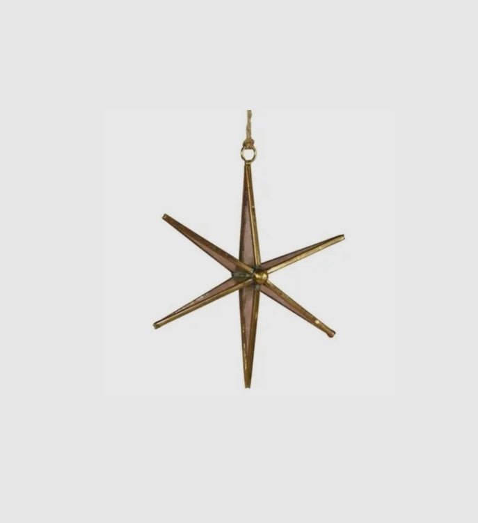 Decorative star-shaped ornament made of brass on a light gray background