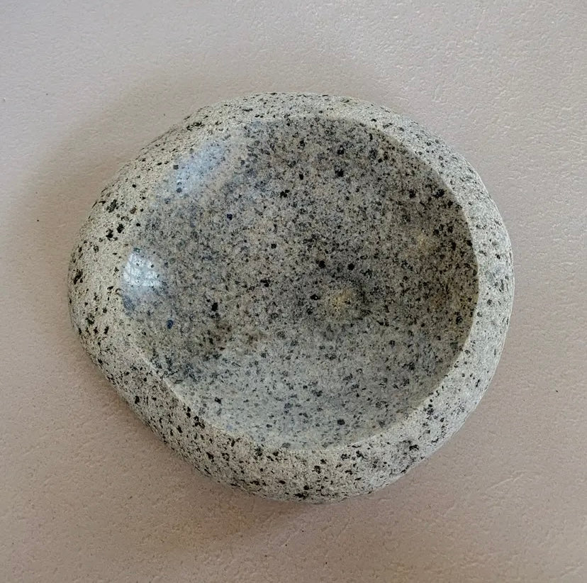 A polished natural beach stone dish with a rough exterior and a finely polished interior.