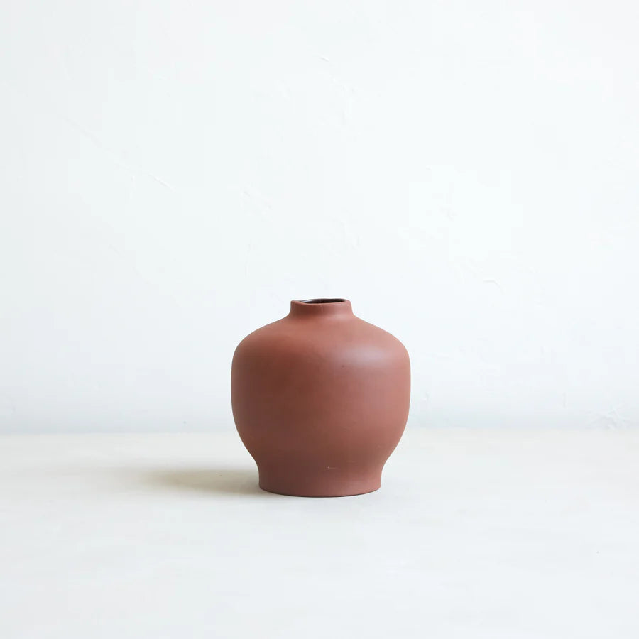 A brown ceramic blossom vase with an organic shape on a plain background.