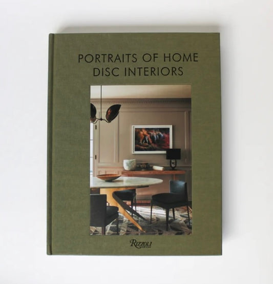 A green hardcover book titled 'Portraits of Home Disc Interiors' showcasing an interior photograph of a modern living room on the cover.