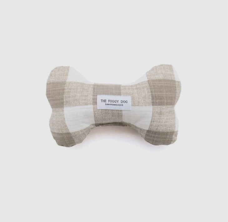 A beige dog bone-shaped toy with a gingham pattern, labeled 'The Roovy Dog' on the side.