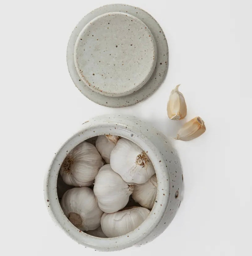 Speckled ceramic farlic keeper from top view with lid off with 7 garlic bulbs visible inside.