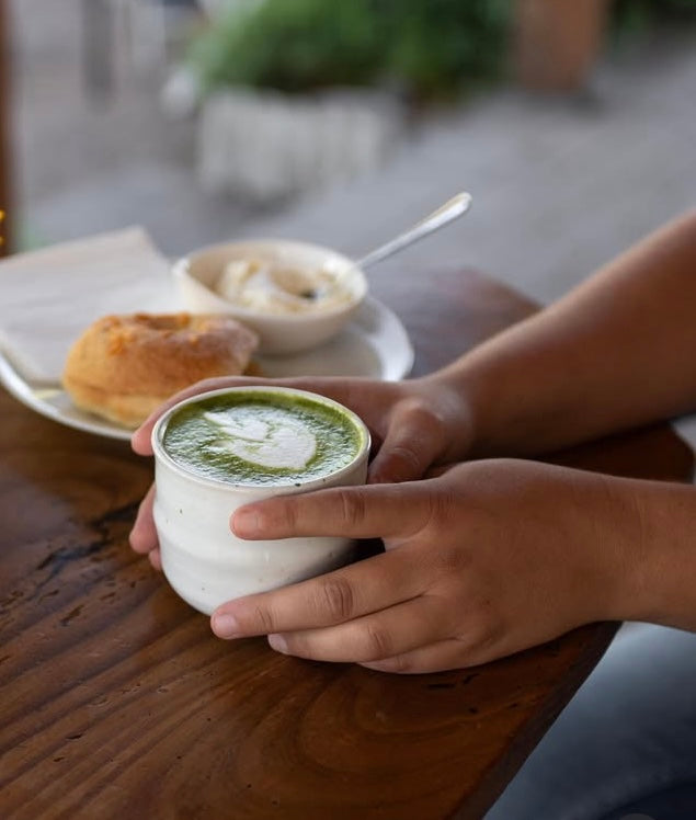 Handmade ceramic tea cup filled with matcha on a wooden table.
