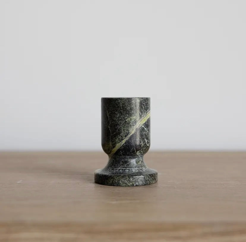 Marble-textured taper holder on a wooden surface with a light gray background