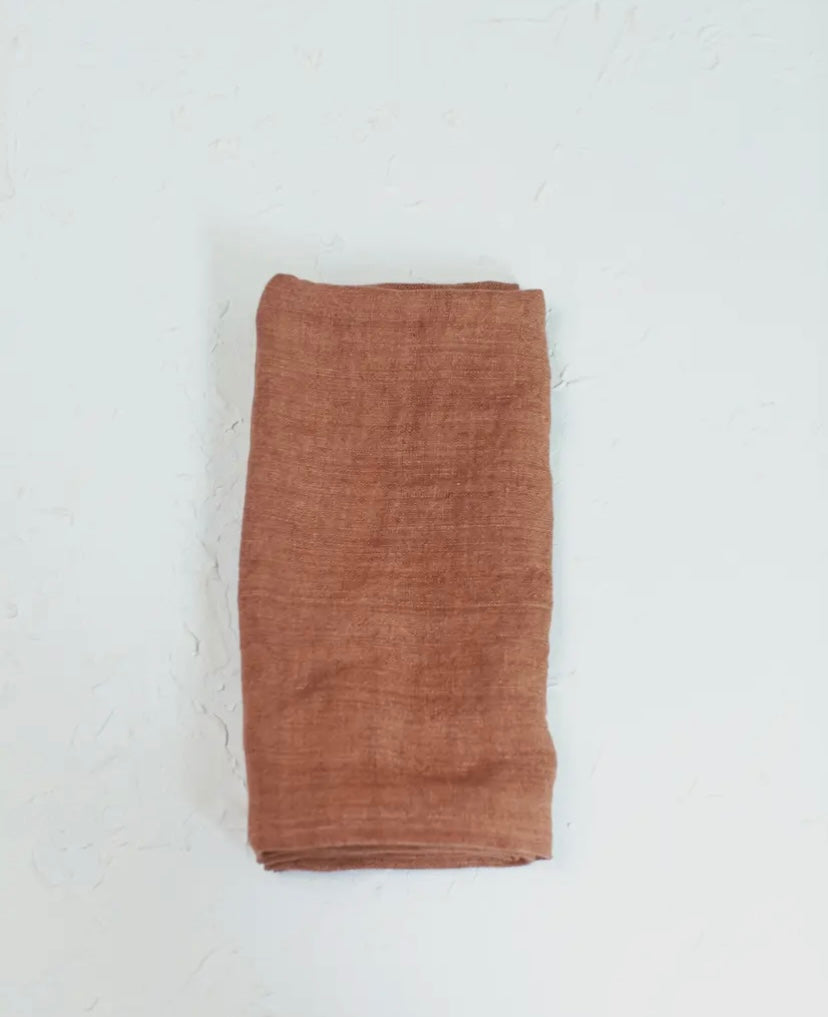 A single russet colored linen napkin folded neatly on a white background.
