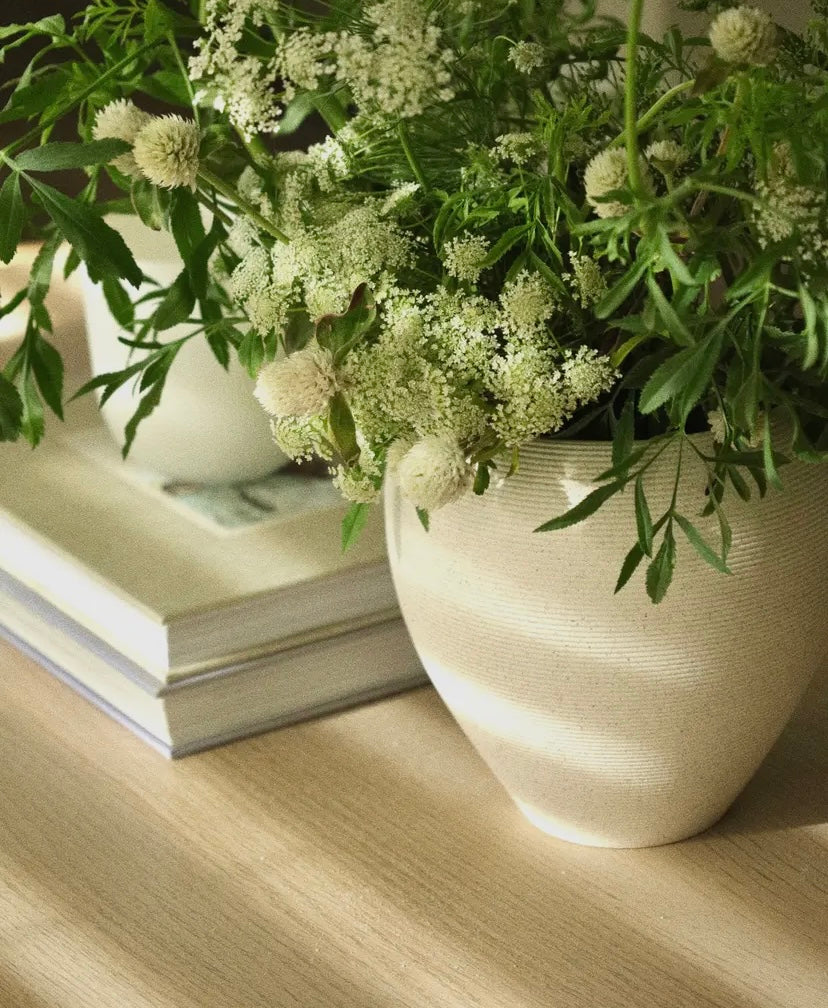 White vase with greenery on a wooden surface