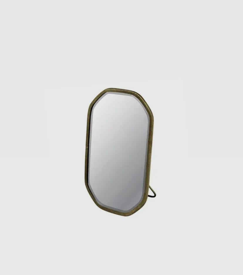 A round beveled glass mirror with a brass frame and built-in easel, suitable for bathroom use.