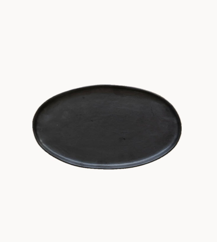 A matte black, oval-shaped stoneware platter with a textured surface. Handmade in Ukraine.