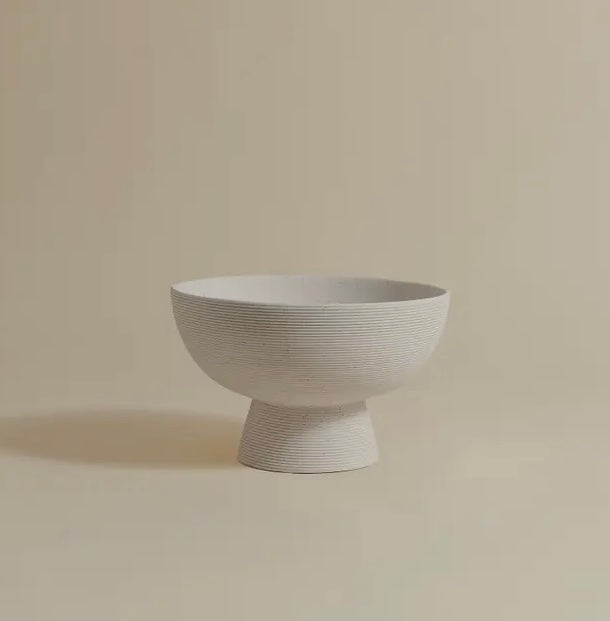 A white, round, pedestal-style bowl on a plain background.