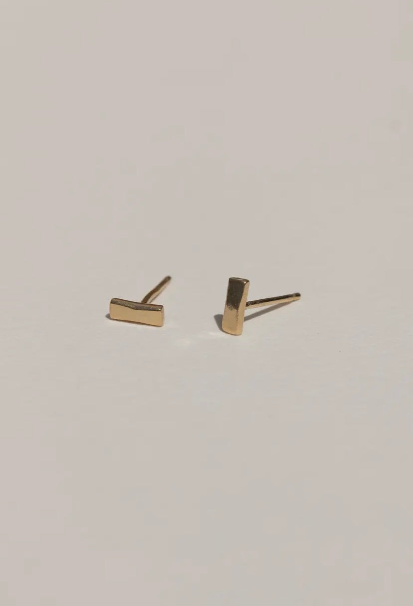 Gold bar stud earrings on a light gray background