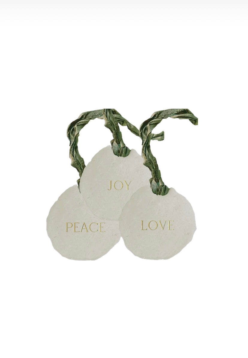 Three white spherical ornaments with green ribbons and gold text on a white background