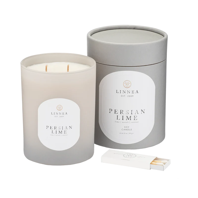 A LINNEA soy candle handcrafted in small batches, with a double cotton wick, in a gray container with the label 'Persian Lime'. A matchbox is included in the image.
