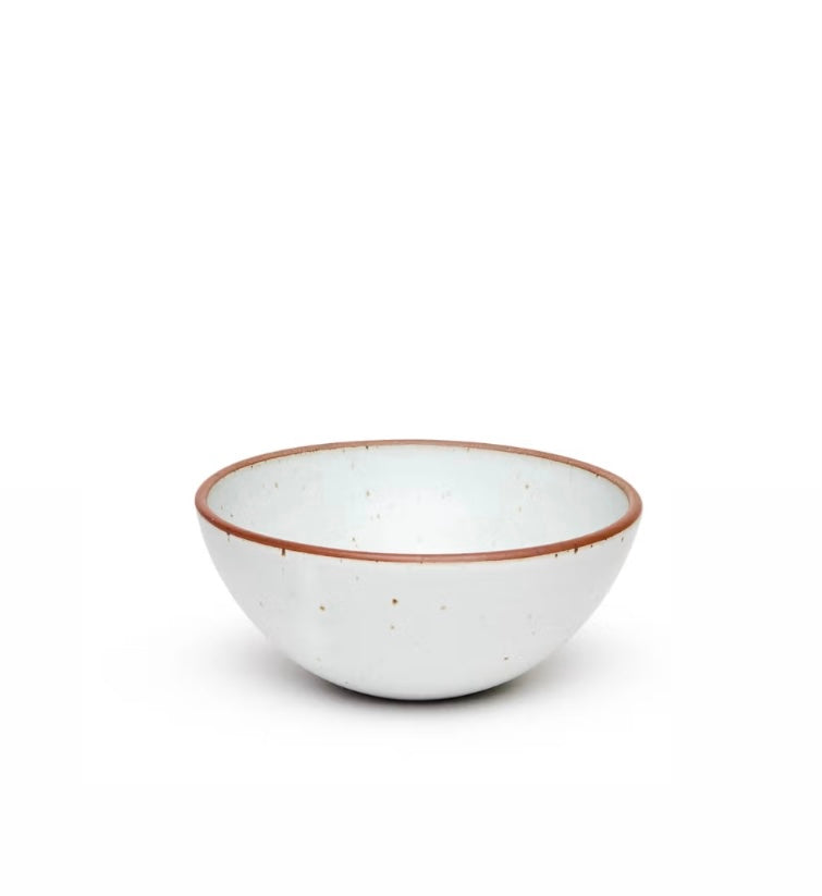A white stoneware popcorn bowl from East Fork with a brown rim, isolated on a white background.