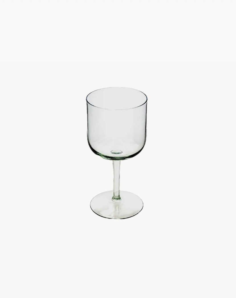 A clear handblown glass wine glass from the Kingdom of Swaziland with a stem, suitable for serving wine or cocktails.