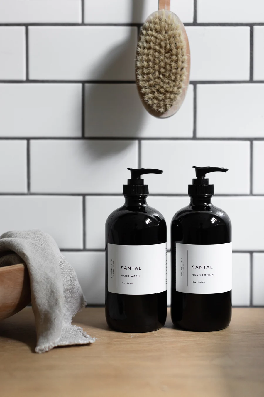 Natural hand moisturizer with woody fragrance, styled beside matching hand wash