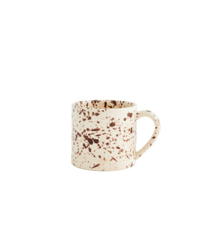 Speckled white and brown ceramic mug on a white background