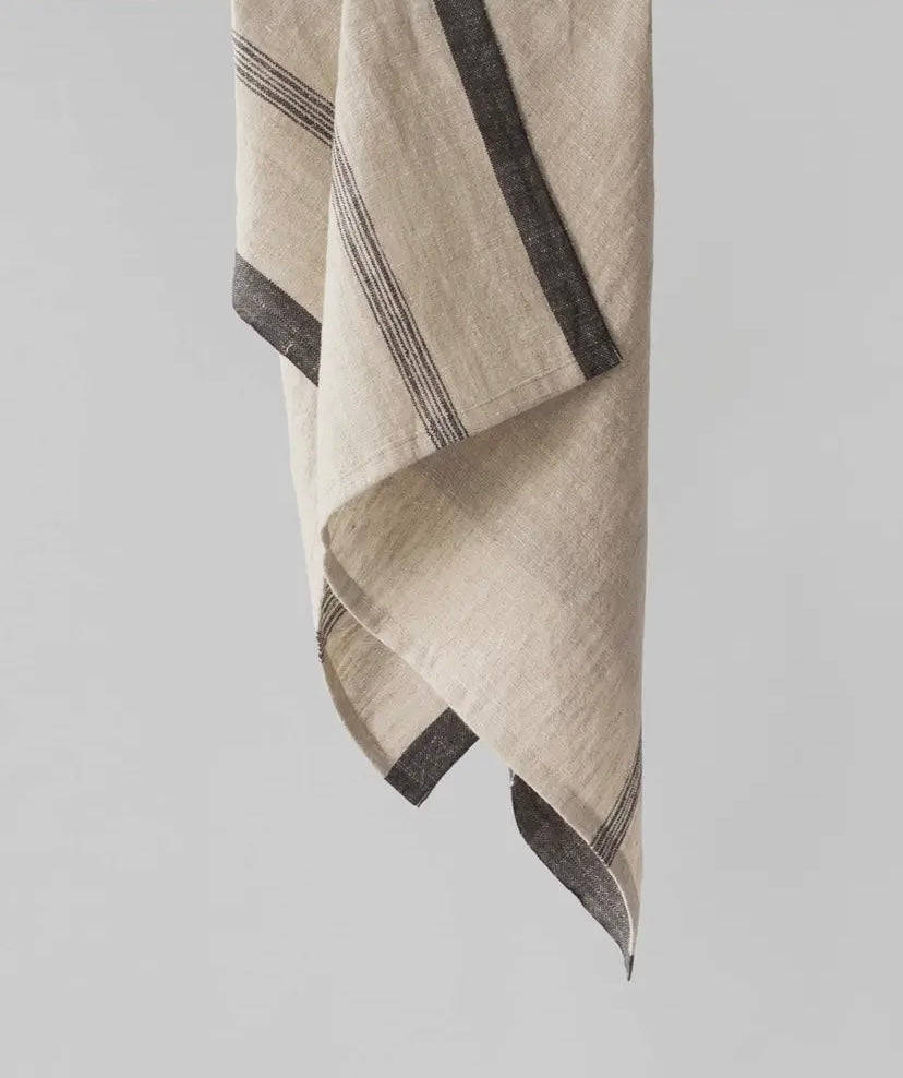 Beige linen towel with black stripes on a light gray background