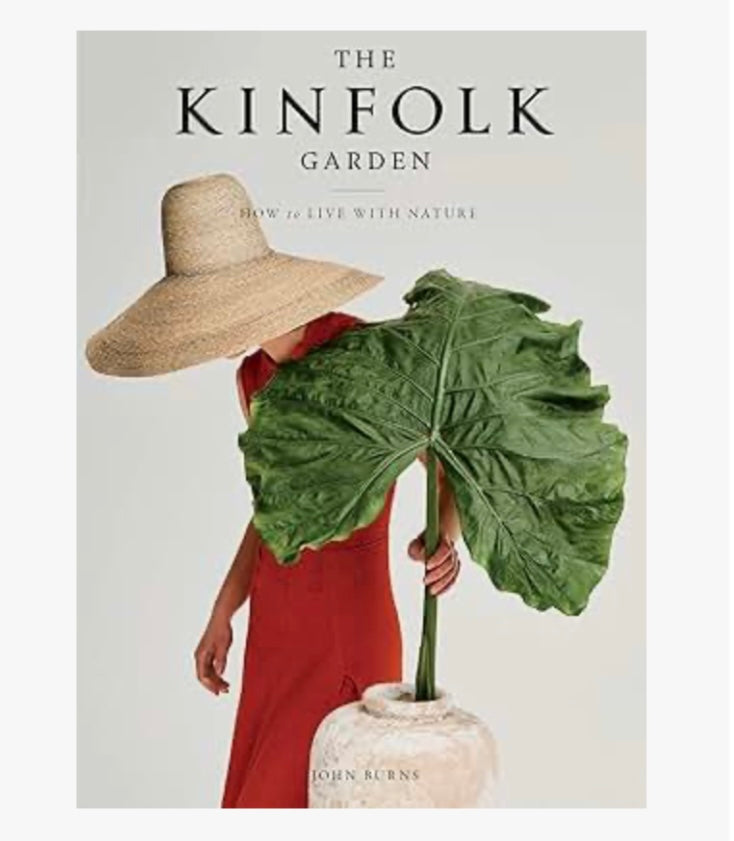 The cover image features a person holding a large green leaf, with a background suggesting a garden or outdoor setting. The book is titled 'The Kinfolk Garden'.