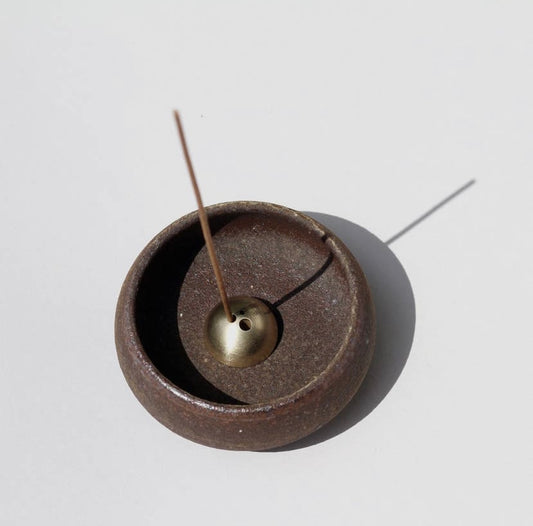 A handmade Japanese-style incense bowl with a brass dome, made of rough stoneware clay, displayed on a white background