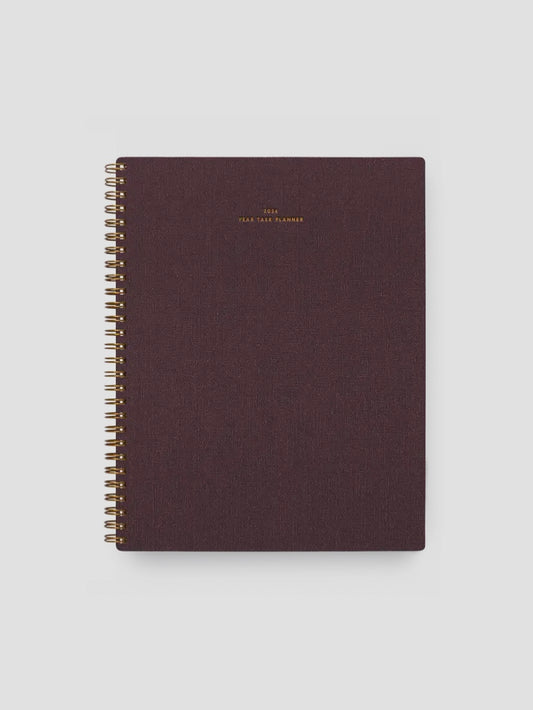 Dark brown planner with gold spiral binding on a light gray background