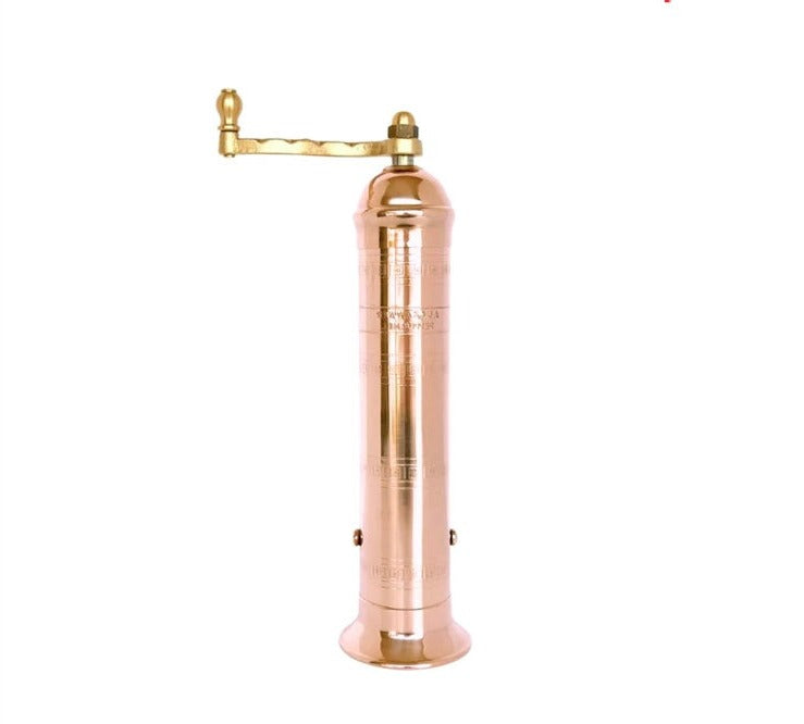 A tall copper pepper mill with a crank on top.  Handmade in Greece.