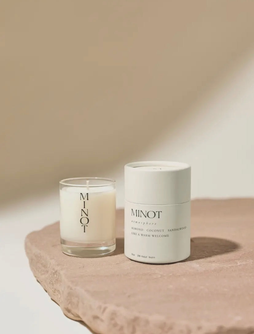 Two 'MINOT' candles on a stone surface with a neutral background