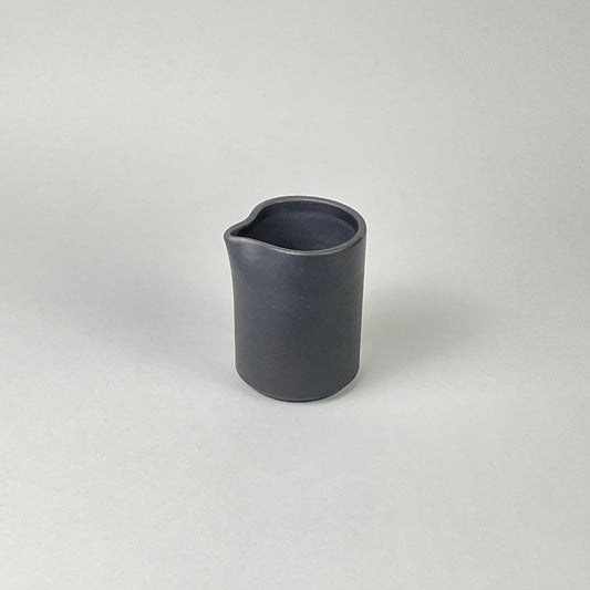 A matte black finish cream pitcher with a minimalist design, handmade in Portugal.