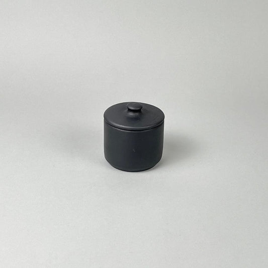 A matte black lidded sugar jar with a minimalist design, placed against a neutral background.