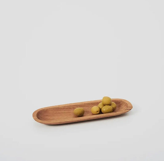 Wooden olive tray with three green olives on a light gray background