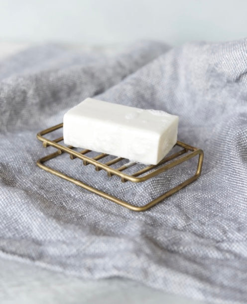 Brass soap stand with white bar of soap on towel.