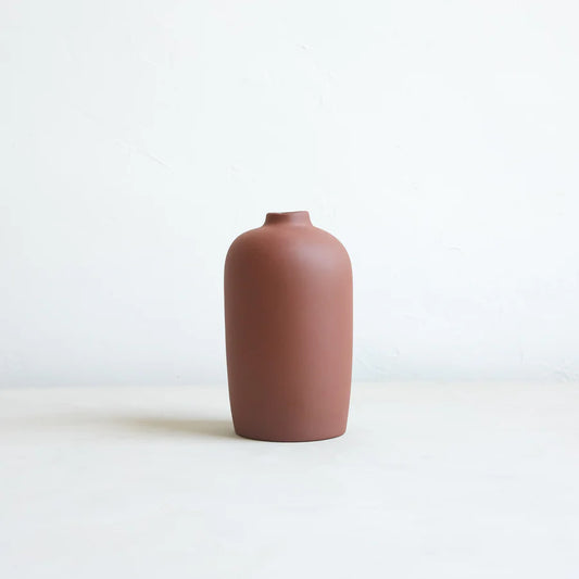 A brown ceramic blossom vase with an organic shape on a plain background.