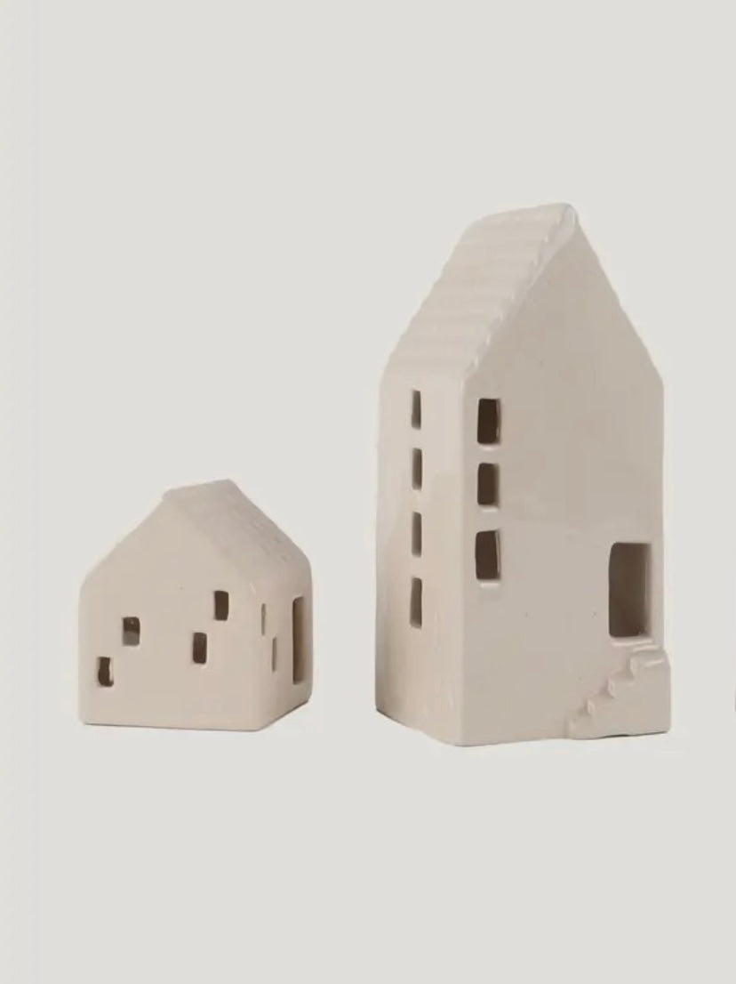 Two beige ceramic house-shaped objects on a light gray background
