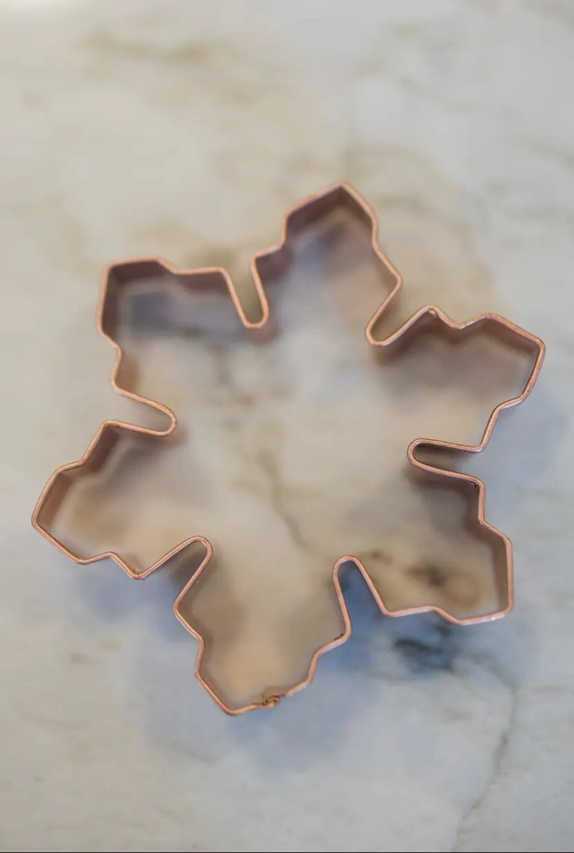 Copper snowflake-shaped cookie cutter on a marble surface