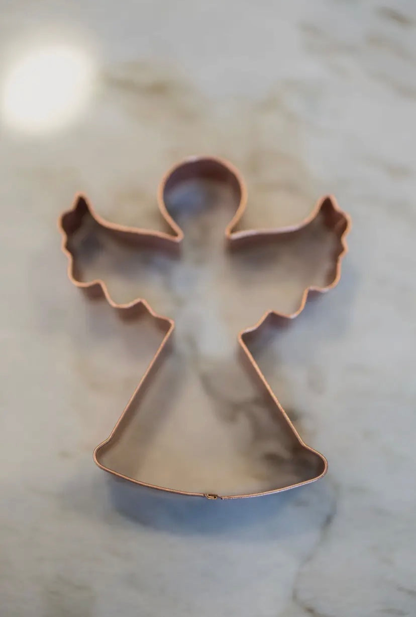 Copper angel-shaped cookie cutter on a marble surface