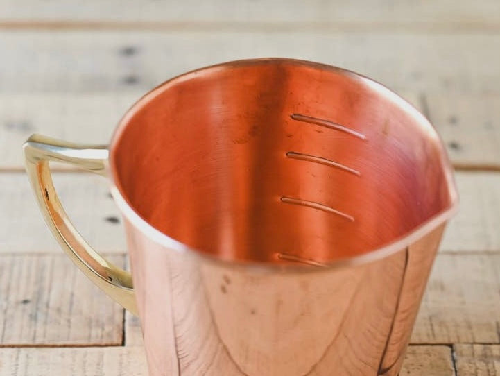 Closeup of coper measuring cup interior.