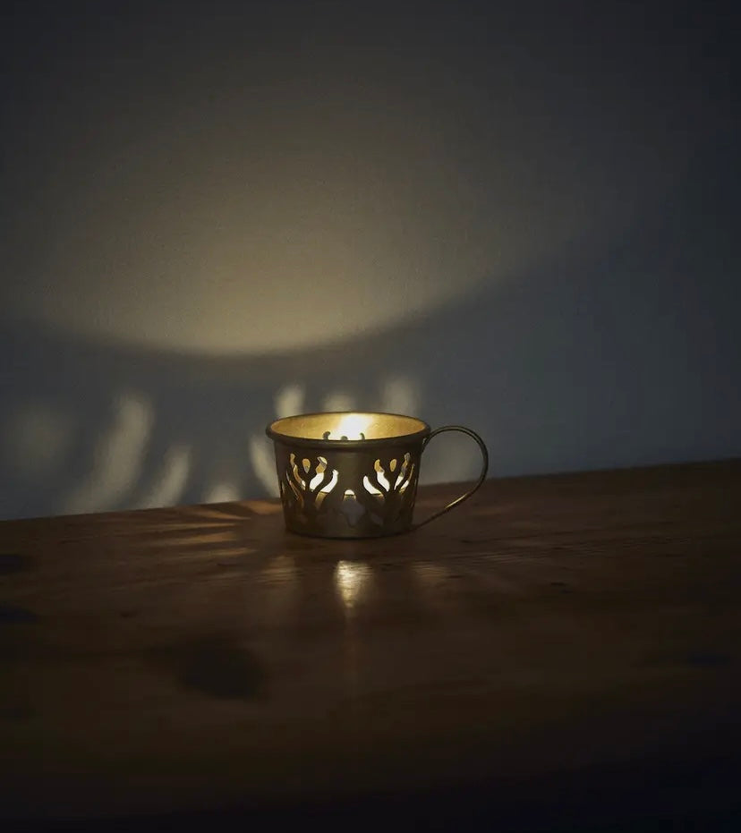 Decorative brass candle holder with intricate design on a dark surface