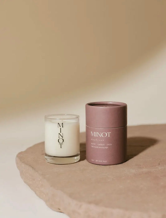 Candle and container with 'MINOT' branding on a beige background