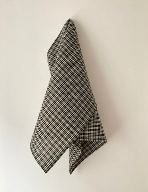 A black and white checkered linen tea towel hanging on a wall.