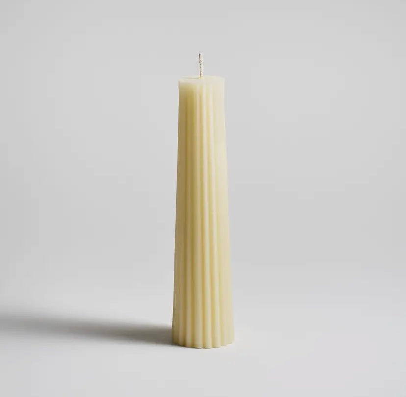 A tall fluted pillar candle made of pure North American beeswax, with a cream tint, hand-poured and finished, displayed against a plain background.