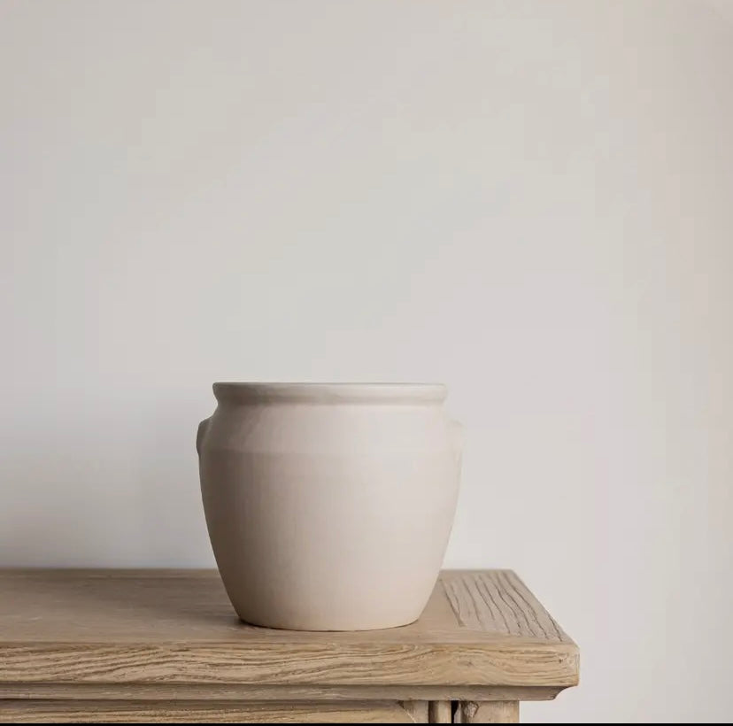 White ceramic confit pot on a wooden surface with a plain background