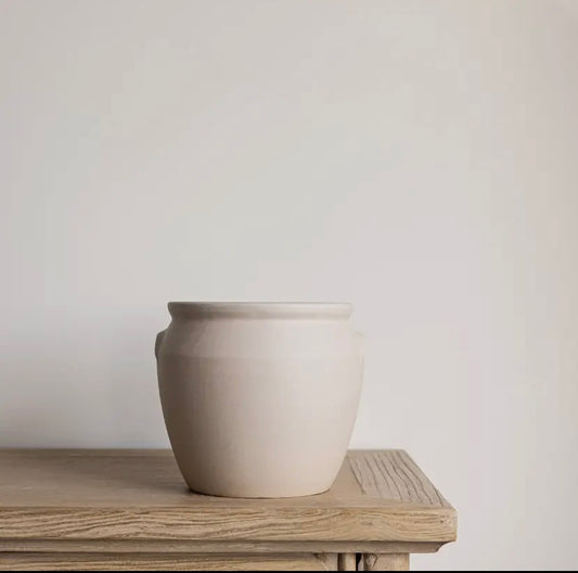 White ceramic confit pot on a wooden surface with a plain background