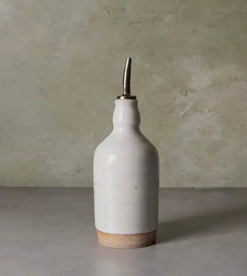 Close-up of ceramic olive oil bottle showing unique glaze and metal spout.
