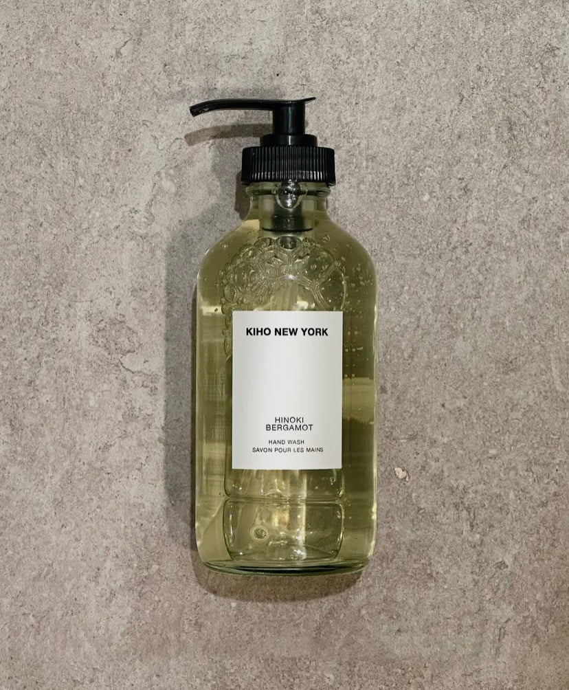 Clear glass bottle with pump and 'KIHO NEW YORK' label on a gray concrete surface