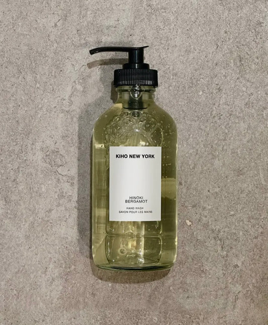 Clear glass bottle with pump and 'KIHO NEW YORK' label on a gray concrete surface