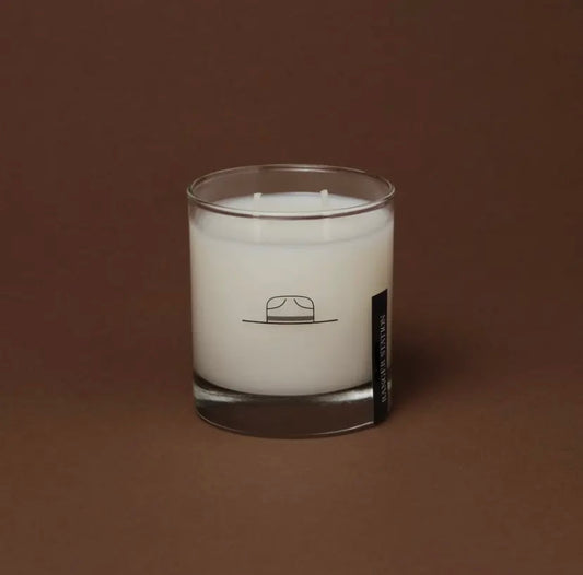 White candle in a glass jar with a logo on a brown background by Ranger Station