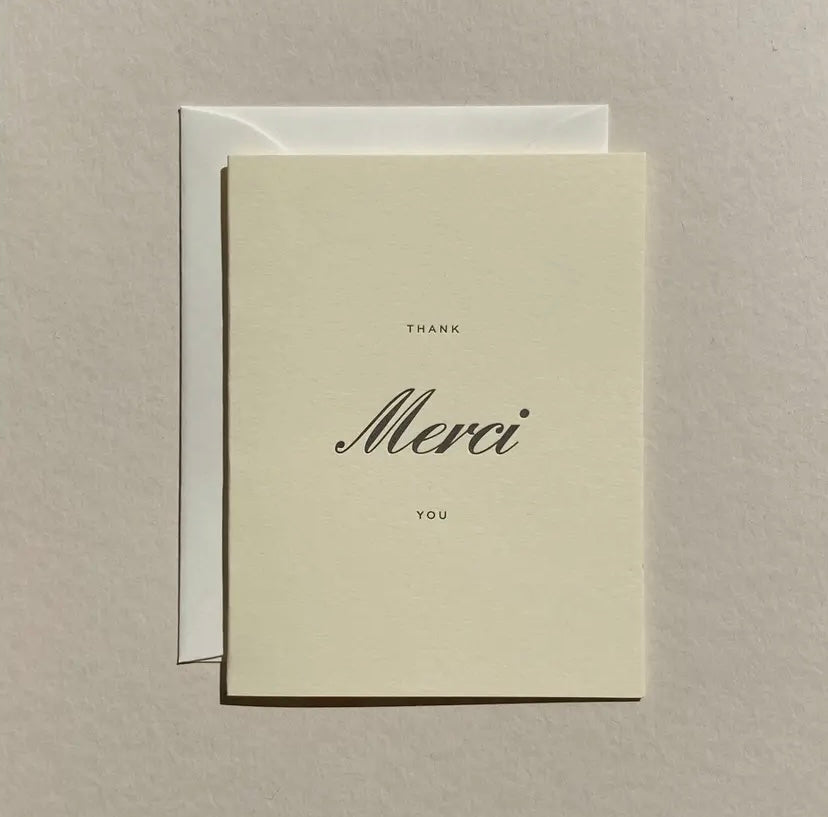Greeting card with 'Merci' and 'Thank you' text on a beige background