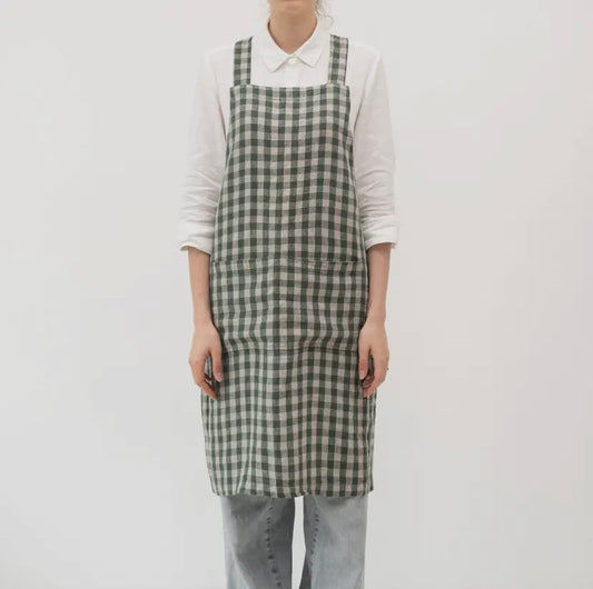 Person wearing a green and white checkered apron on a plain background