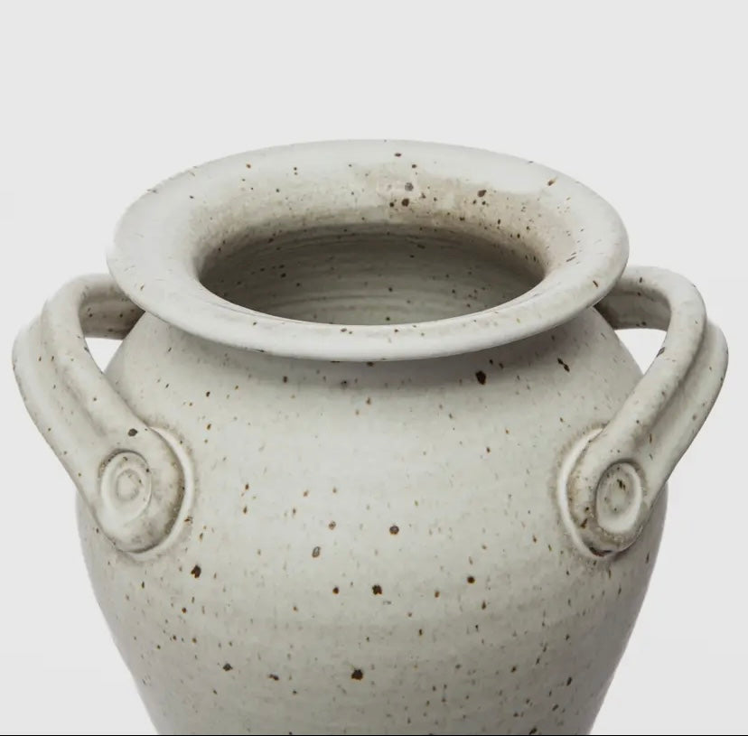 Closeup of white ceramic vase with speckled texture and handles on a light gray background